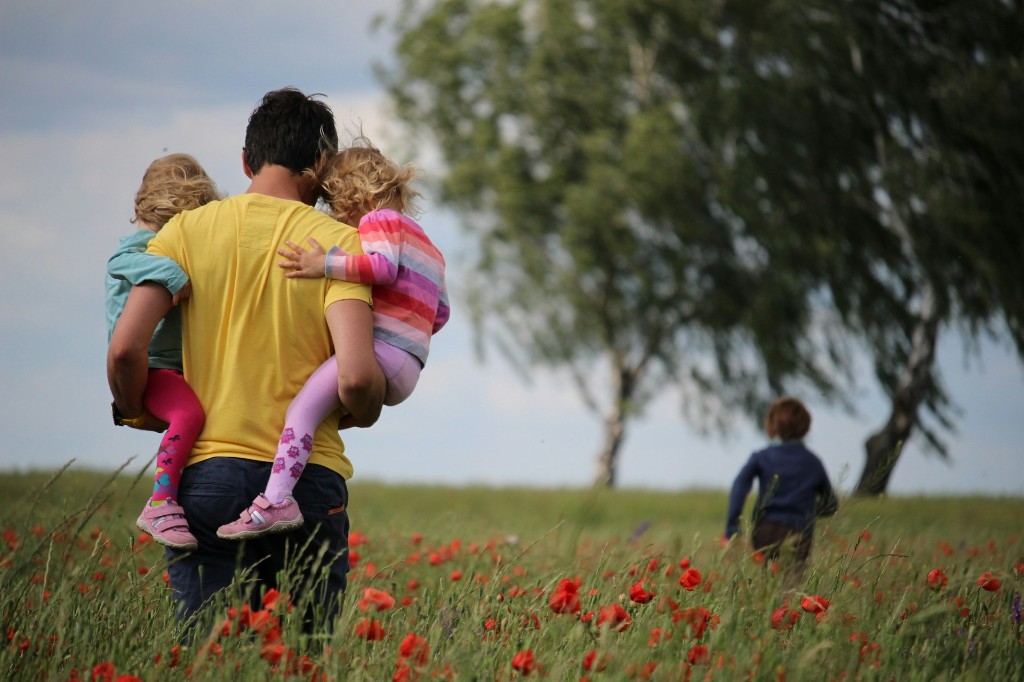An adult and young children in a poppy field—care, protection, and the outdoors