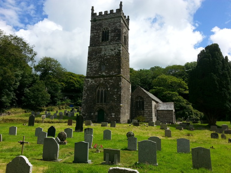 St Julitta’s church tower and churchyard with gravestones at Lanteglos by Camelford, under a clear sky